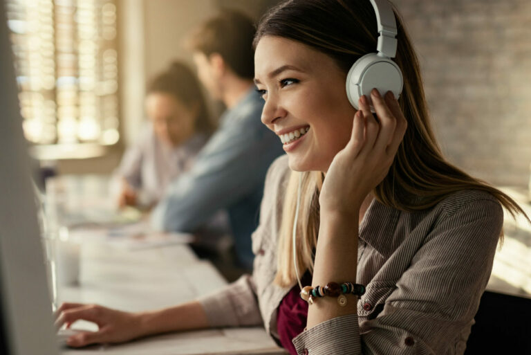 jeune femme affaires heureuse travaillant ordinateur ecoutant musique au casque au bureau ses collegues travaillent arriere plan scaled e1707220803772