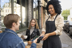 serveuse restaurant avec un terminal de paiement électronique fait payer un client avec une carte sans contact Location terminal de paiement pour évènements